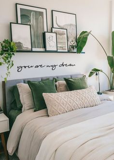 a bed with green pillows and pictures on the wall