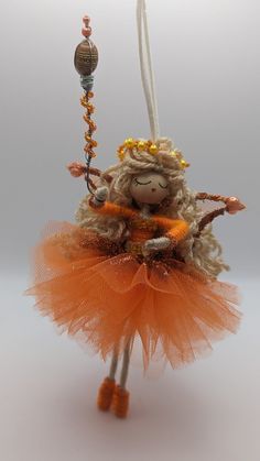 a stuffed animal hanging from a string with orange tutues and beads on it