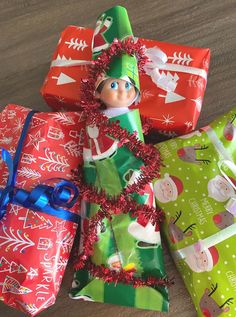 three wrapped presents are sitting on the floor next to each other and one elf is wearing a green hat