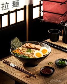 a bowl of ramen with chopsticks and an egg in it on a wooden table