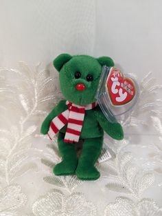 a green teddy bear with a red and white striped scarf on it's neck