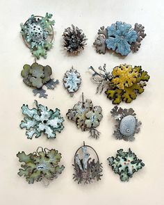 several different types of brooches are displayed on a white surface, including blue and green flowers