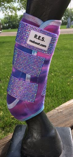 a close up of a horse's boot on a bench in the grass with trees in the background