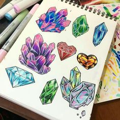 a notebook with different colored crystals on it and markers next to the pages that are open