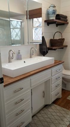 a bathroom with a sink, toilet and shelves on the wall in it's corner