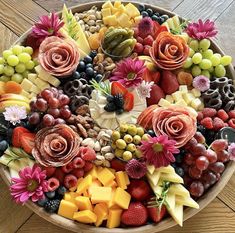 a platter filled with lots of different types of fruits and vegetables on top of a wooden table