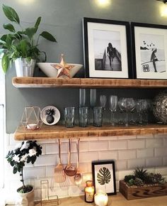 two shelves with pictures and candles on top of them in front of a kitchen counter