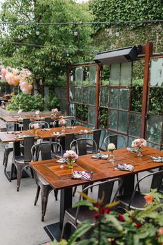 an outdoor dining area with tables, chairs and flowers in vases on the table