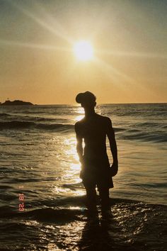 a man standing in the ocean at sunset