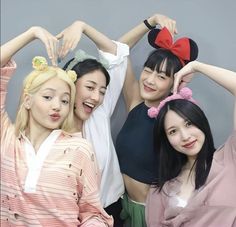 four young women are posing for the camera with mickey ears on their heads and one girl has her hands in her hair