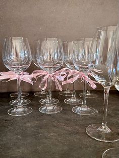 six wine glasses with pink bows on them are lined up in a row and ready to be filled