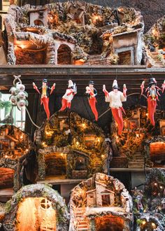 an assortment of christmas decorations on display in a store window with santa's helpers hanging from the ceiling