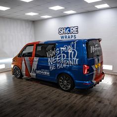 an orange and blue van with graffiti on it's side parked in a garage