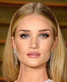 a woman with blonde hair and blue eyes wearing pearls on her head, posing for the camera