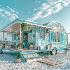 a blue and white trailer parked on top of a sandy beach