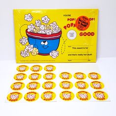 a box of popcorn sitting on top of a white table next to some stickers