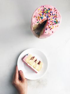 a person holding a plate with a piece of cake on it next to a donut