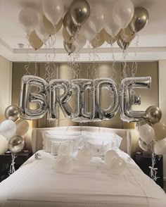 a bed with balloons and the word bride spelled out in large silver letters on it