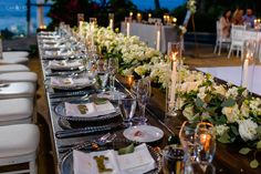 a long table is set with white flowers and candles