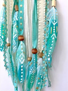 a blue and white dream catcher hanging on a wall with beads, chains and feathers