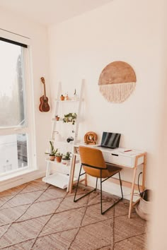 a room with a desk, chair and guitar on the wall next to a window