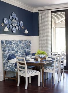 a dining room with blue walls and white furniture on the table, in front of a window