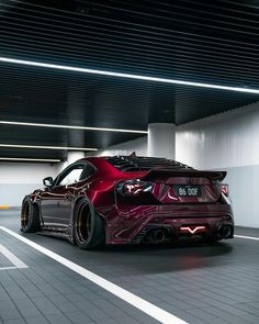 a red sports car is parked in a parking garage with its hood up and lights on