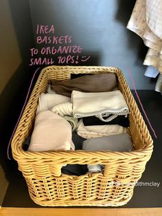 a wicker basket filled with clothes on top of a black table next to a wall