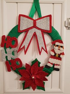 a christmas wreath made out of paper and felt with santa clause, poinsettis and bells