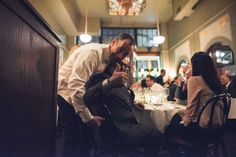 a man standing in front of a table with people sitting around it at a restaurant