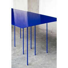 a blue table sitting on top of a cement floor next to a white wall in an empty room