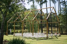 an outdoor ceremony area with white chairs and a wooden structure in the middle, surrounded by trees