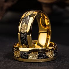 two gold wedding rings with black diamonds on them