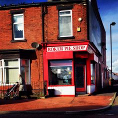 a man pushing a stroller in front of a red brick building with the word rocker pie shop written on it