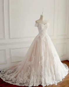 a wedding dress is displayed on a mannequin in front of a white wall