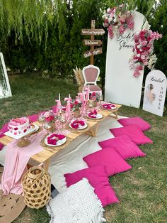 a table set up with pink and white plates, napkins, and other items