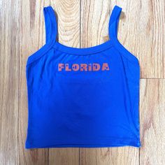 Florida blue and orange tank with star lettering. Perfect for a tailgate or showing spirit! Orange Tops For Women, Casual Tops With Team Name For Tailgating, Blue Sleeveless Top For Sports Events, Blue Racerback Top With Graphic Print, Blue Graphic Print Racerback Tank Top, Blue Racerback Tank Top With Graphic Print, Blue School Spirit Tops For College, Blue College Tops With School Spirit, Casual Sleeveless Tank Top With Team Name