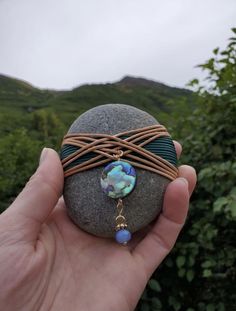 a hand holding a rock with a bead on it