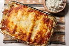 a casserole dish with meat and cheese in it next to a bowl of rice