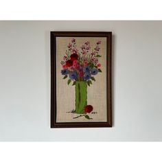 a painting hanging on the wall above a vase with purple and red flowers in it