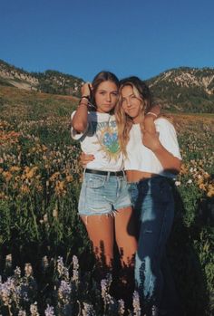 two girls are standing in a field with wildflowers