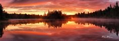 the sun is setting over a lake surrounded by trees