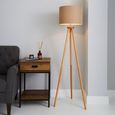 a living room with a gray couch and wooden floor lamp