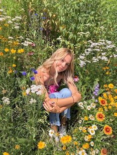 a woman kneeling in a field of wildflowers