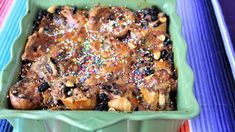 a green dish filled with cake and sprinkles on top of a colorful table cloth