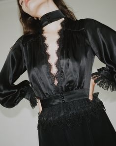 Our Rita Blouse in black features a plunging V neckline trimmed with delicate Venise lace, a true waistline cinch and soft billowing sleeves all trimmed with Alençon lace and embroidered ruffled tulle lace. 100% Silk Charmeuse lined with Silk Habutai Three satin covered pearl buttons for each closure Dry clean only Each piece is made to order and handcrafted in our atelier. Slight variations may occur as each piece is unique. V-neck Lace Trim Top For Party, V-neck Lace Top With Lace Trim For Party, Black Lace Trim V-neck Top, Black Lace Top With Lace Trim For Formal Occasions, Black Lace Top With Lace Cuffs For Party, Feminine V-neck Lace Top For Party, Black Lace Top With Lace Trim For Formal Events, V-neck Lace Trim Top For Night Out, V-neck Lace Top With Lace Trim For Night Out