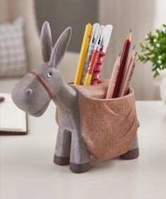 a toy donkey with pencils and markers in it's pouch on a table