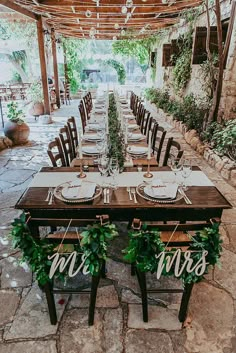 a table set up for a wedding with mr and mrs signs hanging from the ceiling