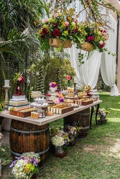 a table with flowers and desserts on it in the middle of a garden area