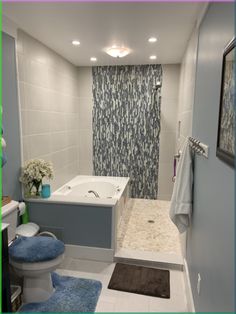 a bathroom with blue rugs and white fixtures on the walls, along with a walk in shower